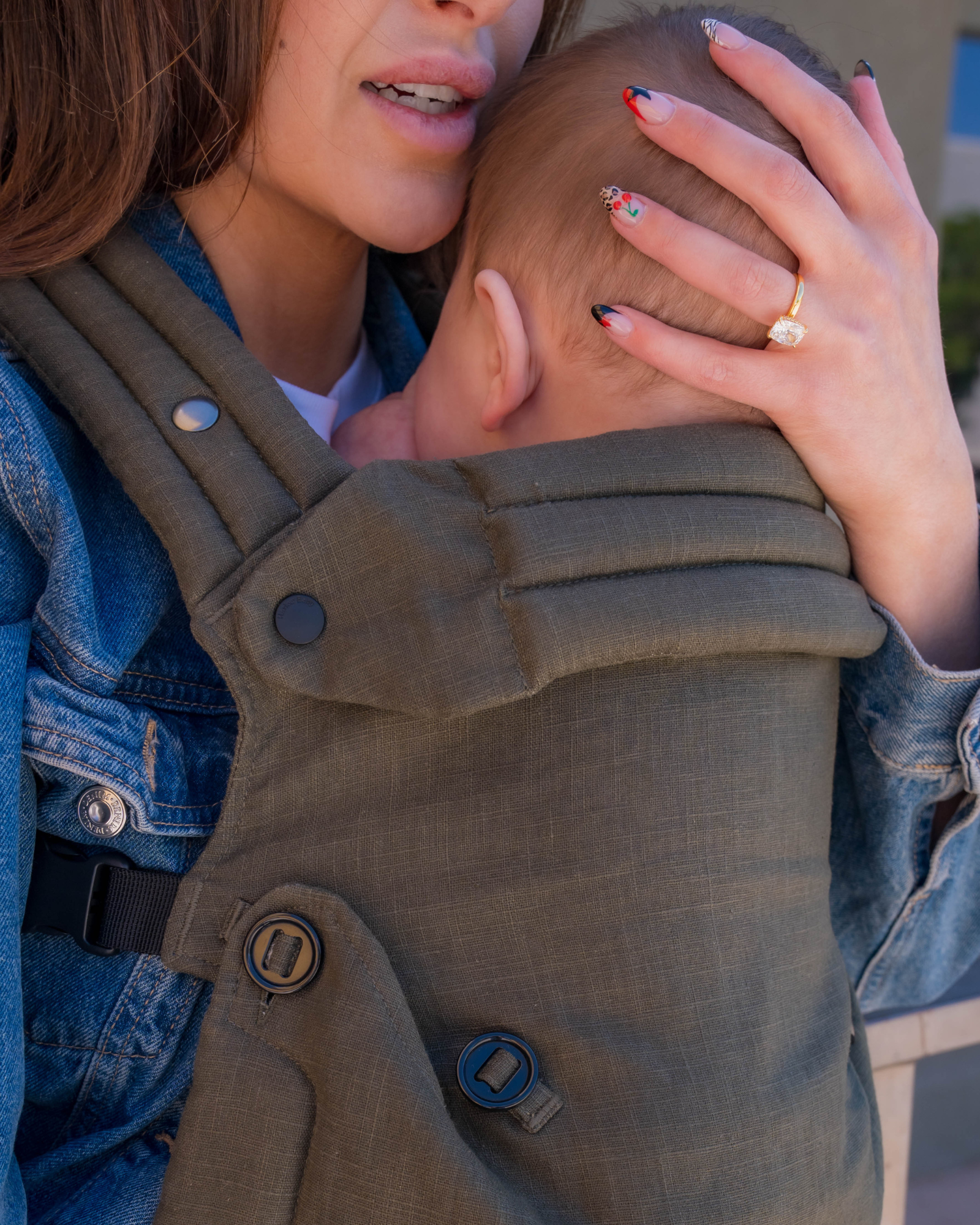 olive green baby carrier with inward-facing carry position