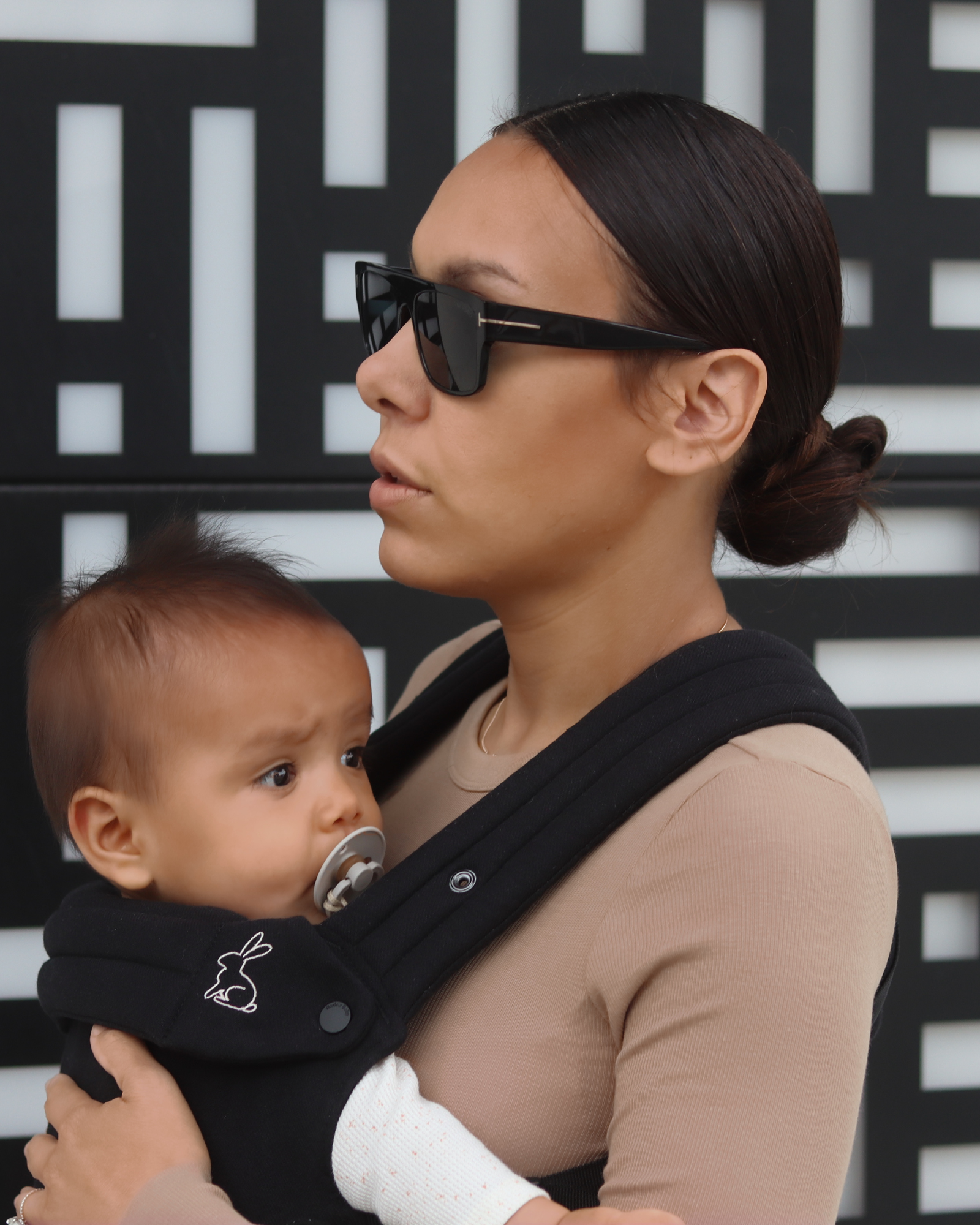Mom wearing ergonomic black baby carrier side view