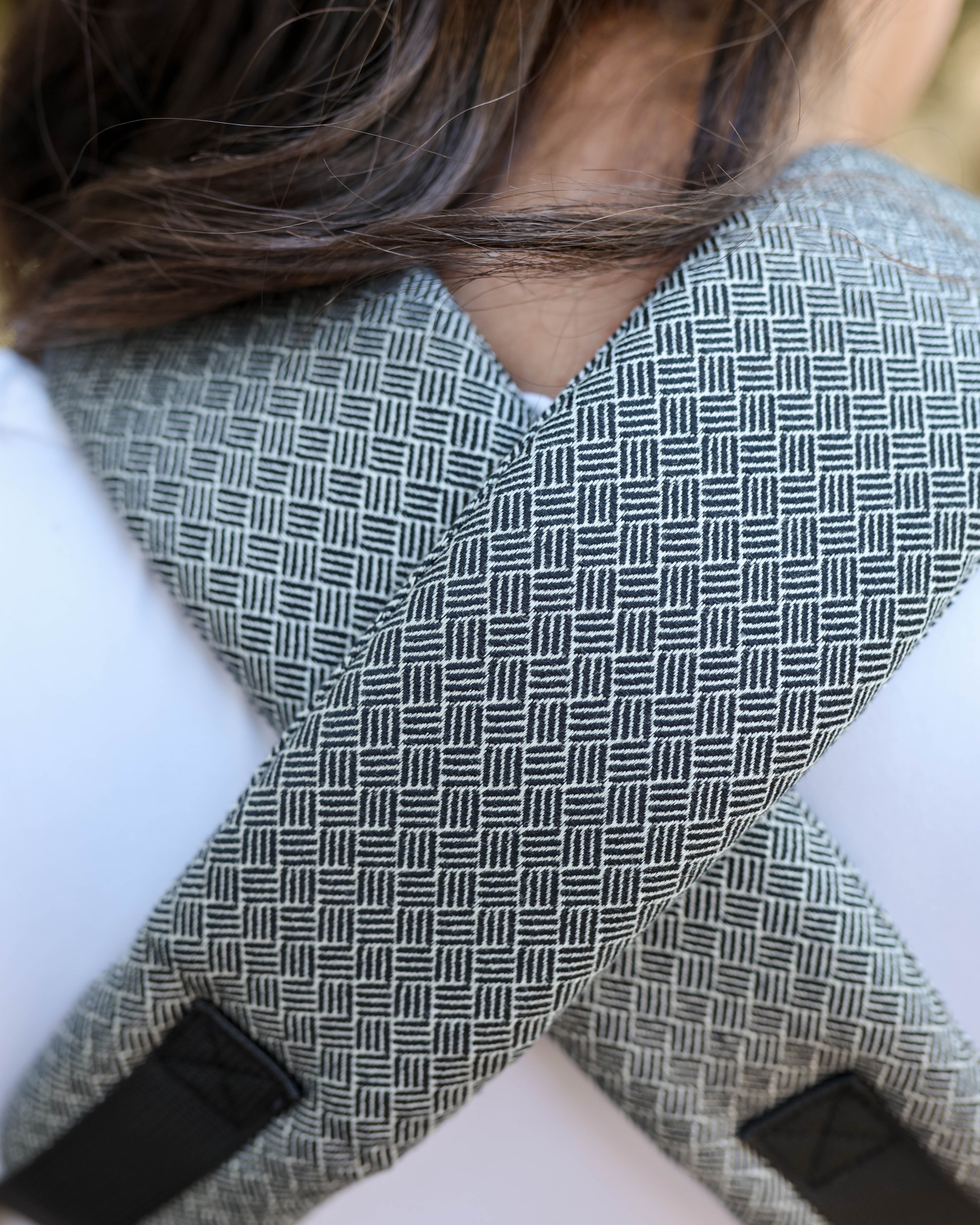 Close-up of a person wearing a woven cross-back support belt with black and white jacquard woven