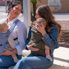Mom wearing ergonomic olive green baby carrier with baby outdoors