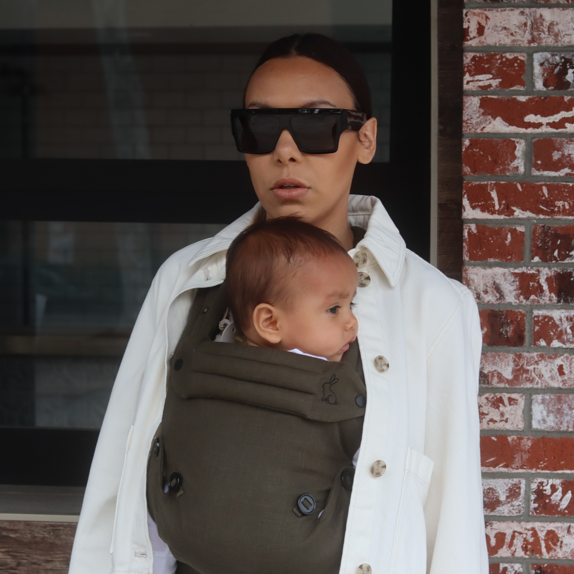 olive green baby carrier with inward-facing carry position