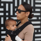 Mom wearing ergonomic black baby carrier side view