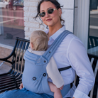 Mom wearing blue baby carrier with baby  outdoors