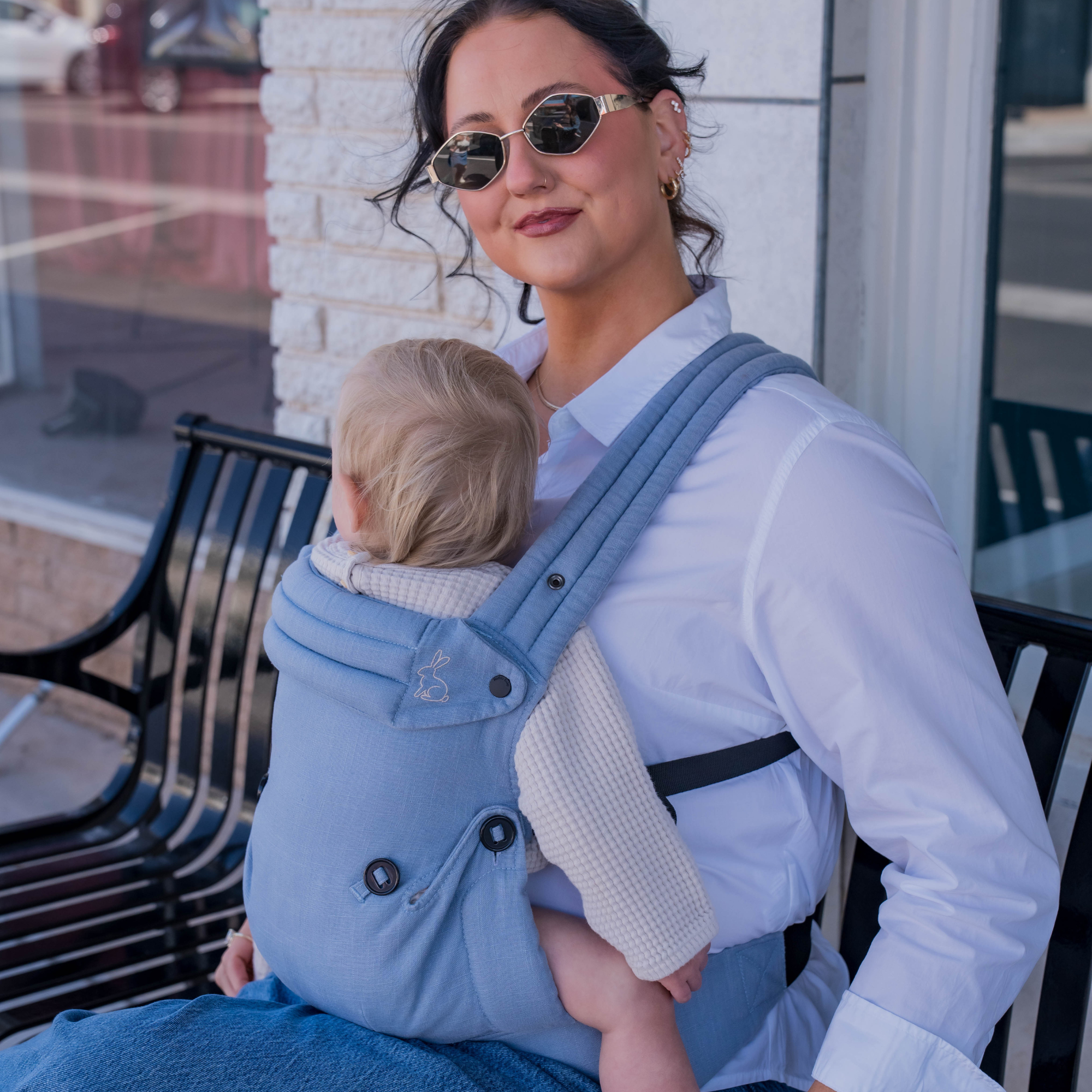 Mom wearing blue baby carrier with baby  outdoors