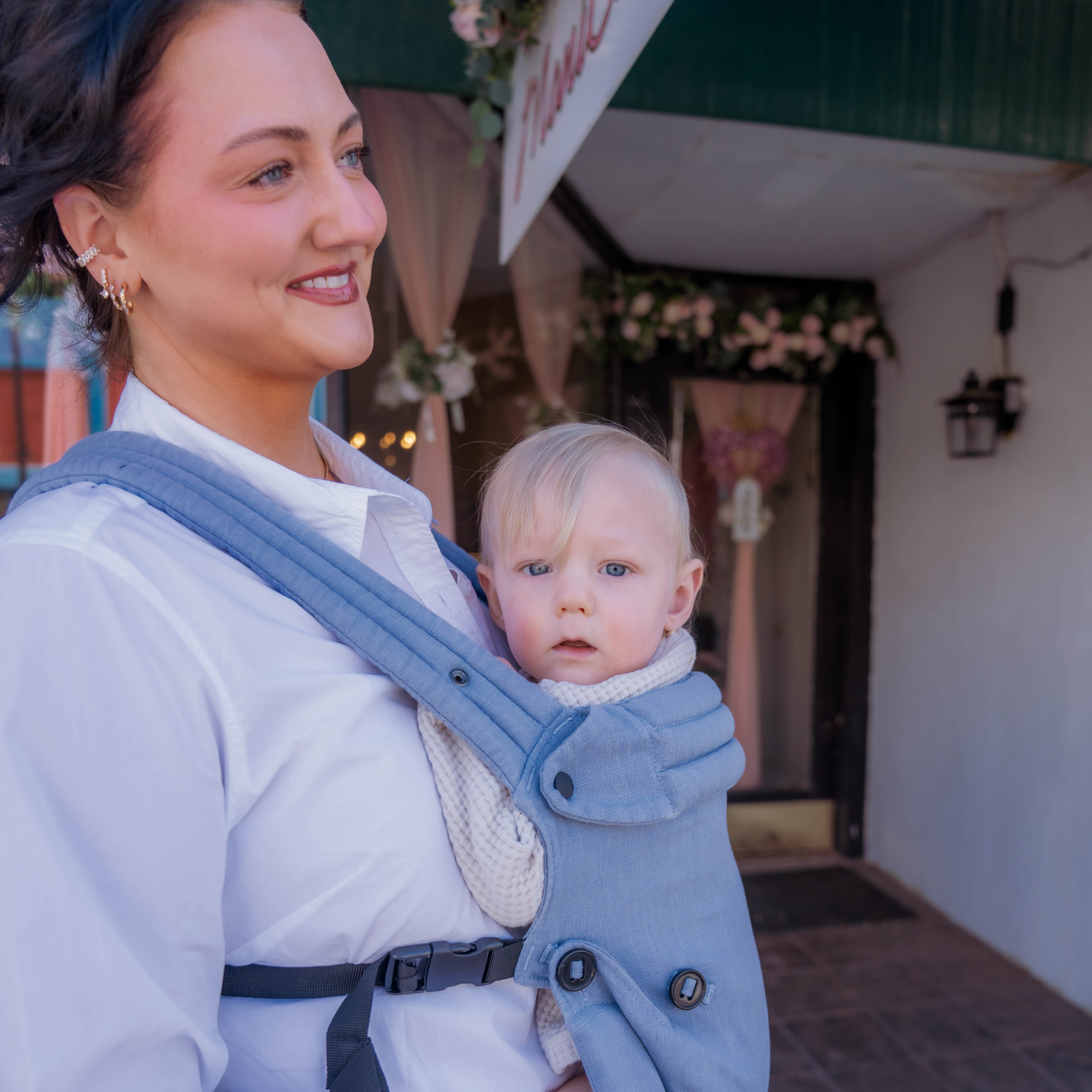 Mom wearing ergonomic blue baby carrier with baby while shopping