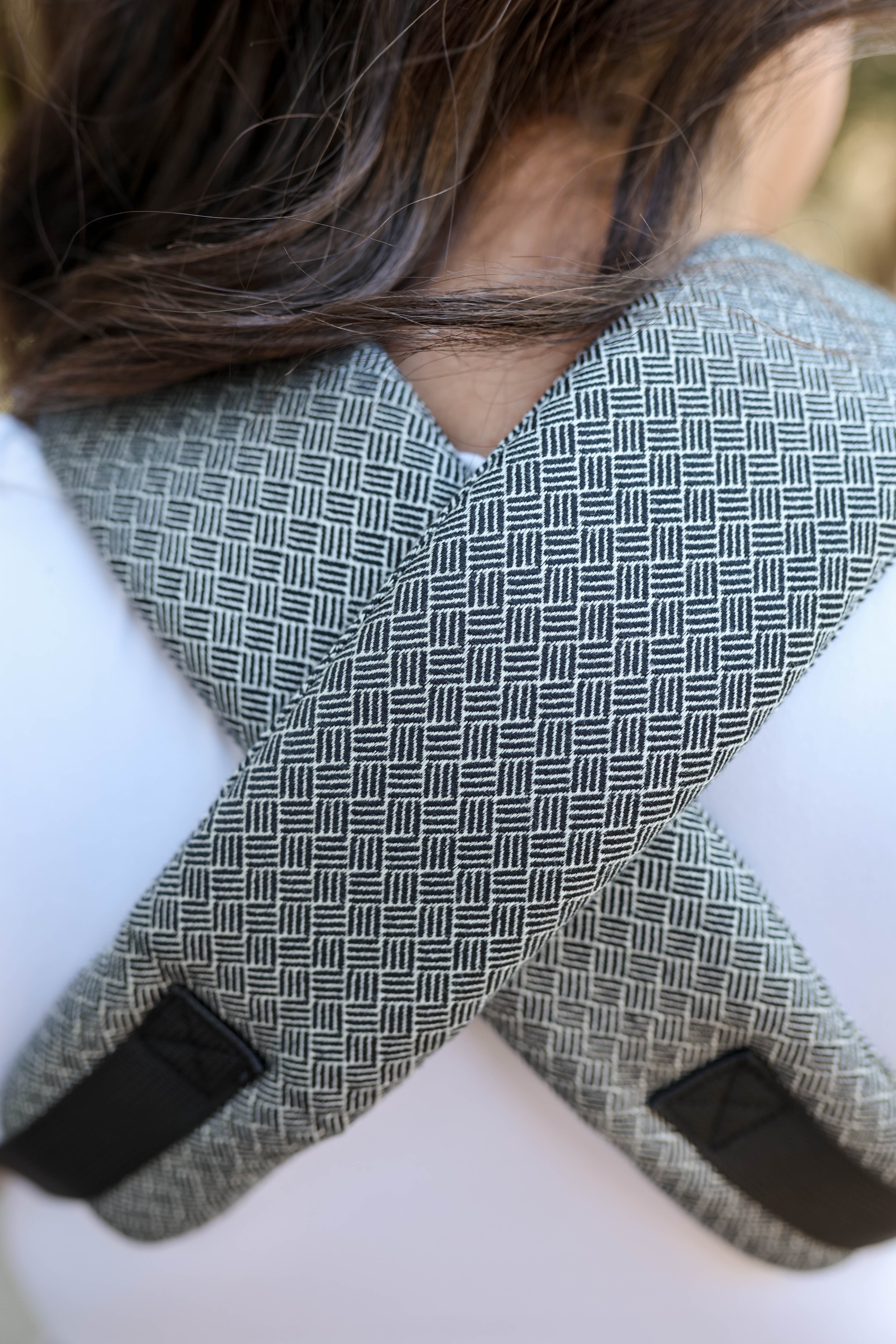 Close-up of a person wearing a woven cross-back support belt with black  and white jacquard woven 